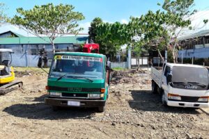 Two Isuzu flatbed trucks from the Blueline fleet parked front-on at a job site