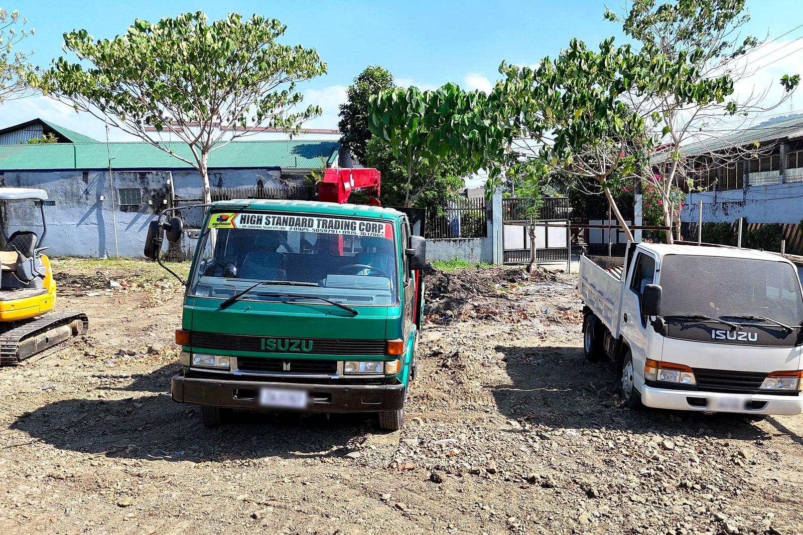 Two Isuzu flatbed trucks from the Blueline fleet parked front-on at a job site