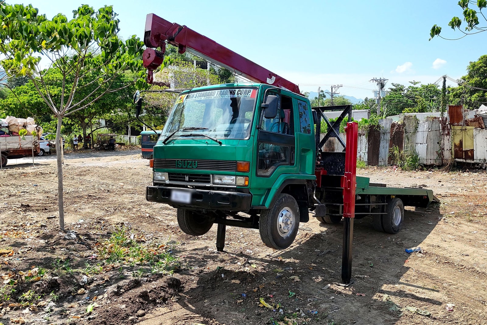 A green boom truck with crane arm extended at a job site