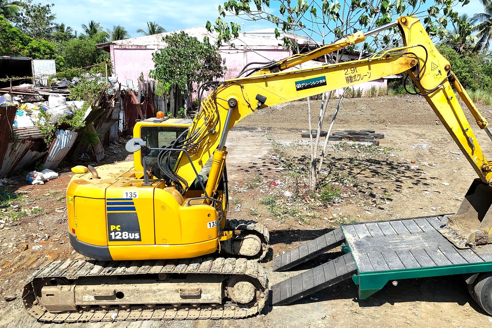 A mini excavator being loaded onto a trailer for delivery